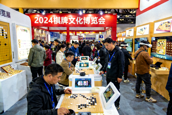 棋牌文化博览会展览现场，观众在展台前体验棋牌文化互动项目